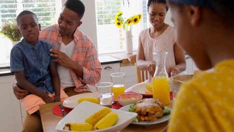 Vista-Frontal-De-Una-Familia-Negra-Feliz-Comiendo-Comida-En-Una-Mesa-De-Comedor-En-Una-Casa-Cómoda-4k