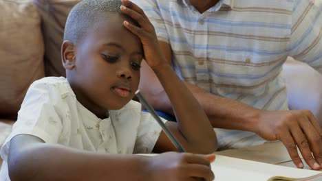 Front-view-of-young-black-father-helping-his-son-with-homework-in-a-comfortable-home-4k