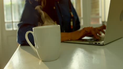 Close-up-of-steam-coming-out-of-coffee-cup-on-dining-table-in-kitchen-of-comfortable-home-4k