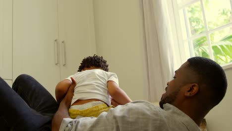 Side-view-of-young-black-father-playing-with-son-and-lying-on-floor-in-a-comfortable-home-4k
