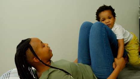 Side-view-of-young-black-mother-playing-with-her-son-on-bed-in-a-comfortable-home-4k