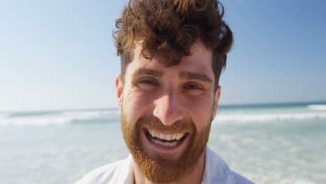 Happy-young-man-looking-at-camera-on-the-beach-4k