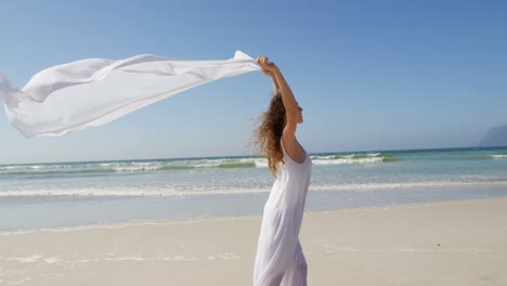 Woman-standing-by-the-sea-with-a-waving-scarf.at-beach-4k