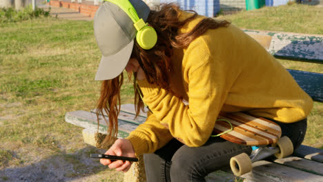 Seitenansicht-Einer-Jungen-Kaukasischen-Frau,-Die-Am-Strand-Musik-Hört-Und-Ihr-Mobiltelefon-Benutzt,-4k