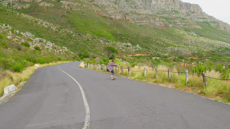 Front-view-of-stylish-young-woman-doing-skateboard-trick-on-downhill-at-countryside-road-4k