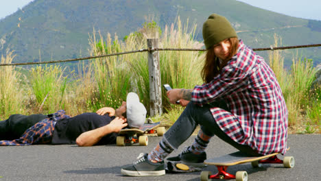 Side-view-of-young-caucasian-skateboarders-relaxing-on-skateboard-on-a-sunny-day-4k