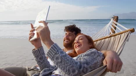 Couple-using-digital-tablet-at-beach-4k