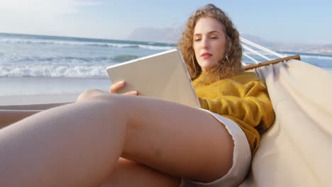 Mujer-Usando-Tableta-Digital-En-Hamaca-En-La-Playa-4k