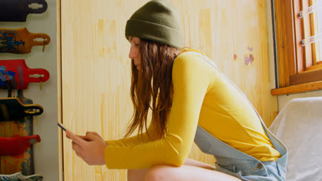 Side-view-of-young-caucasian-woman-texting-on-mobile-phone-in-a-workshop-4k