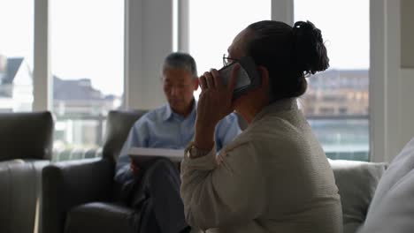 Vista-Lateral-De-Una-Anciana-Asiática-Hablando-Por-Teléfono-Móvil-En-Una-Cómoda-Casa-4k