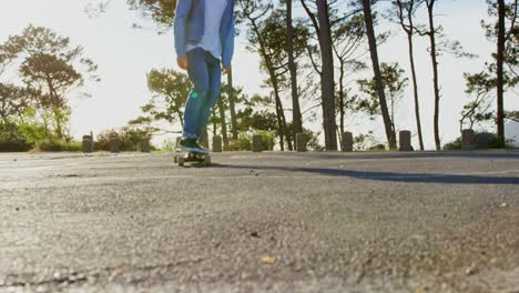 Front-view-of-young-male-skateboarder-riding-on-skateboard-on-country-road-4k