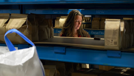 Front-view-of-caucasian-female-worker-checking-packed-goods-in-warehouse-4k