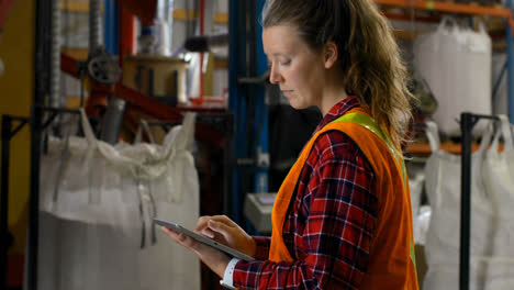 Side-view-of-caucasian-female-worker-working-on-digital-tablet-in-warehouse-4k
