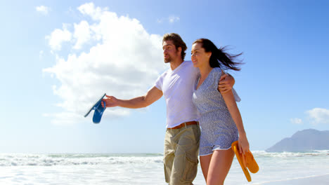 Side-view-of-young-caucasian-couple-walking-at-beach-on-a-sunny-day-4k