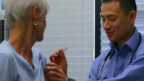 Young-Asian-male-doctor-injecting-senior-patient-in-the-clinic-4k