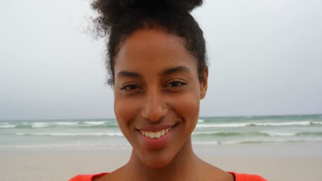 Vorderansicht-Einer-Jungen-Schwarzen-Frau,-Die-Lächelt-Und-In-Die-Kamera-Am-Strand-Blickt,-4k