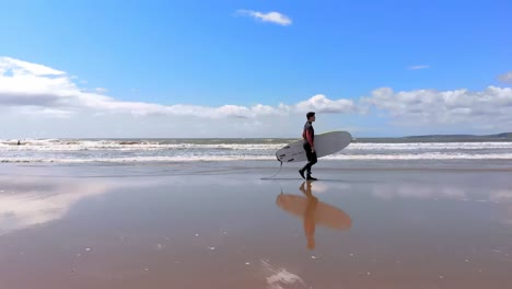 Male-surfer-walking-with-surfboard-at-beach-on-a-sunny-day-4k