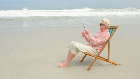 Side-view-of-old-caucasian-senior-man-taking-selfie-with-mobile-phone-at-beach-4k