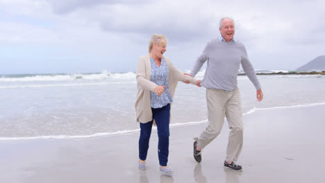 Front-view-of-old-caucasian-senior-couple-running-on-the-beach-4k