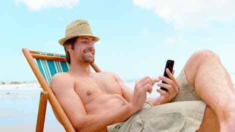 Seitenansicht-Eines-Jungen-Kaukasischen-Mannes,-Der-Am-Strand-Sein-Mobiltelefon-Benutzt,-4k