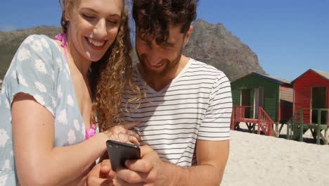 Couple-using-mobile-phone-at-beach-4k