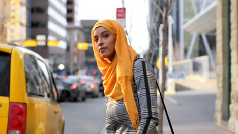 Side-view-of-young-Asian-woman-in-hijab-using-mobile-phone-in-the-city-4k