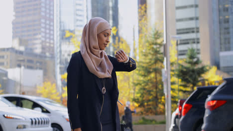 Seitenansicht-Einer-Jungen-Asiatischen-Frau-Im-Hijab,-Die-In-Der-Stadt-Ihr-Mobiltelefon-Benutzt,-4K