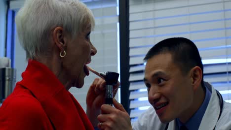 Side-view-of-young-Asian-male-doctor-examining-a-senior-patient-in-the-clinic-4k