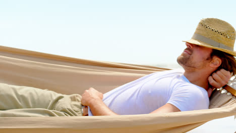 Side-view-of-caucasian-man-sleeping-in-hammock-at-beach-4k