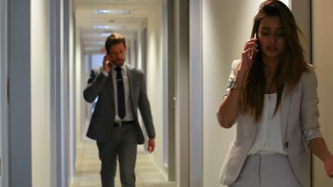 Businesswoman-talking-on-mobile-phone-at-corridor-4k
