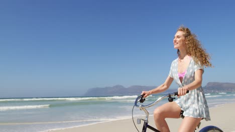 Woman-riding-a-bicycle-at-beach-on-a-sunny-day-4k