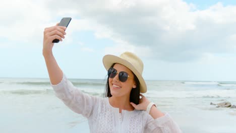 Side-view-of-young-caucasian-woman-taking-selfie-with-mobile-phone-at-beach-4k