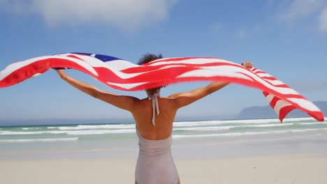 Frau-Steht-Am-Meer-Mit-Einer-Wehenden-Amerikanischen-Flagge.-Am-Strand-4k