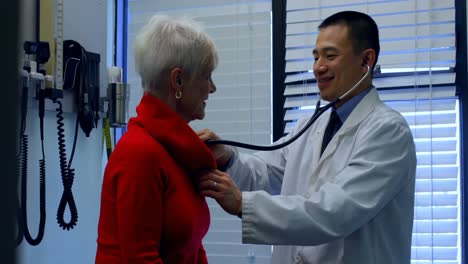 Side-view-of-young-Asian-male-doctor-examining-a-senior-patient-in-the-clinic-4k