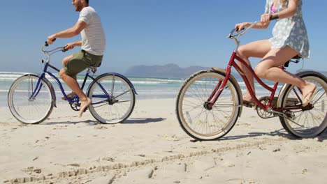 Couple-riding-bicycle-at-beach-on-a-sunny-day-4k