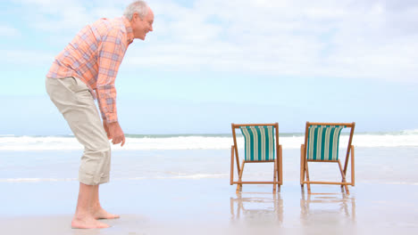 Side-view-of-old-caucasian-senior-couple-rolling-pants-up-at-beach-4k