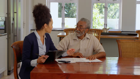 Mixed-race-female-real-estate-agent-discussing-over-property-with-senior-man-at-home-4k