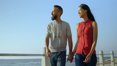 Young-mixed-race-couple-pointing-at-sea-while-walking-on-promenade-4k
