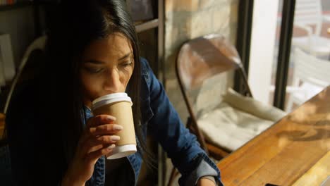 High-angle-view-of-young-mixed-race-woman-drinking-coffee-and-using-laptop-in-cafe-4-4k