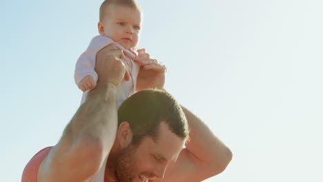 Side-view-of-mid-adult-caucasian-father-carrying-baby-on-shoulder-on-a-sunny-day-4k