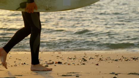 Seitenansicht-Eines-Kaukasischen-Surfers-Mittleren-Alters,-Der-Mit-Einem-Surfbrett-Am-Strand-Spaziert,-4k