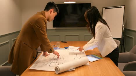 Side-view-of-young-Asian-business-people-discussing-over-blueprint-in-the-conference-room-4k