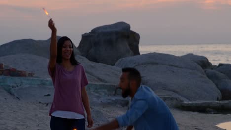 Happy-young-mixed-race-couple-having-fun-with-sparklers-at-beach-4k