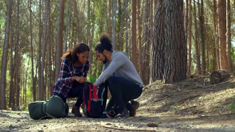 Young-couple-checking-hiking-backpack-in-the-forest-4k