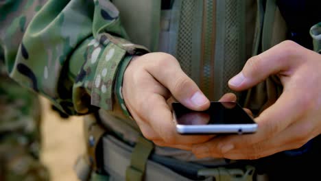 Mittelteil-Eines-Kaukasischen-Militärsoldaten,-Der-Während-Der-Militärischen-Ausbildung-Ein-Mobiltelefon-Benutzt-4k
