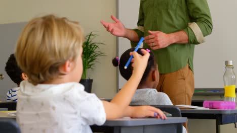 Adult-Caucasian-male-schoolteacher-teaching-schoolkids-in-classroom-at-school-4k