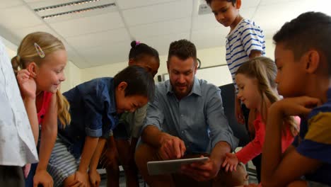 Adult-Caucasian-male-teacher-teaching-school-kids-on-digital-tablet-in-classroom-4k