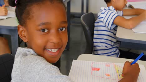 Fröhliches-Afroamerikanisches-Schulmädchen,-Das-Am-Schreibtisch-In-Einem-Klassenzimmer-In-Der-Schule-4k-Lernt