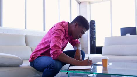 Handsome-African-american-male-executive-writing-on-a-diary-in-modern-office-4k