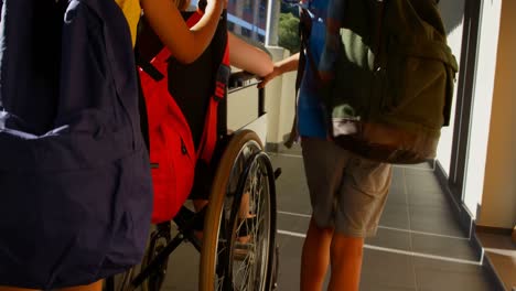 Schulkinder-Schieben-Behindertes-Schulmädchen-Im-Rollstuhl-Auf-Dem-Flur-4k